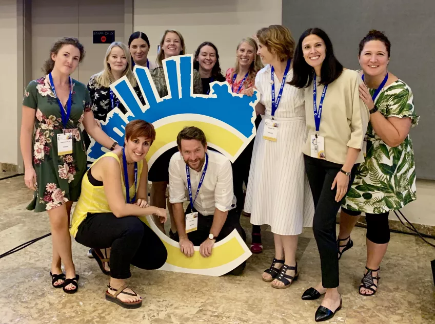 A group of researchers posing around a logo of complement conference in Madrid